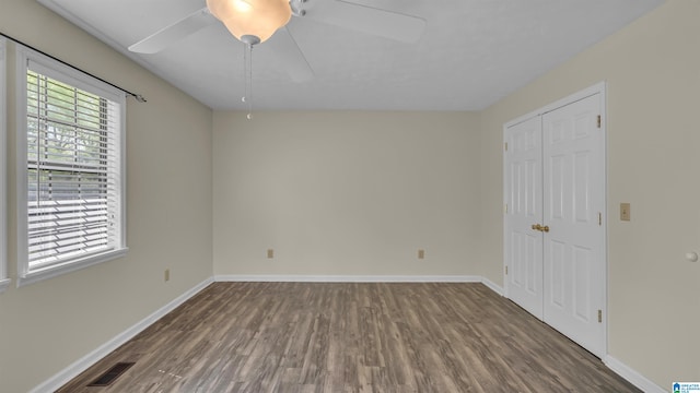 unfurnished bedroom with wood finished floors, baseboards, a closet, and visible vents
