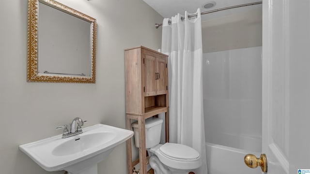 bathroom with shower / tub combo with curtain, a sink, and toilet