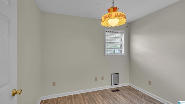 unfurnished room featuring visible vents, baseboards, and wood finished floors