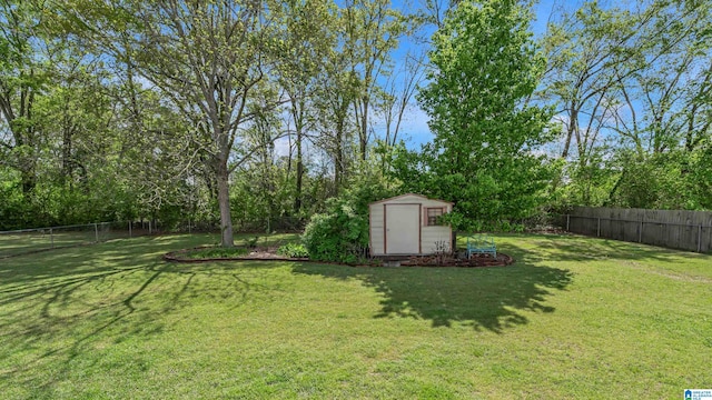 view of yard featuring a storage shed, a fenced backyard, and an outbuilding