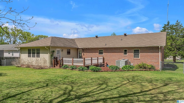 back of property with brick siding, central AC unit, a wooden deck, a yard, and fence