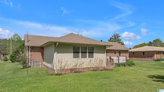 view of side of home with a yard, fence, a shingled roof, and crawl space