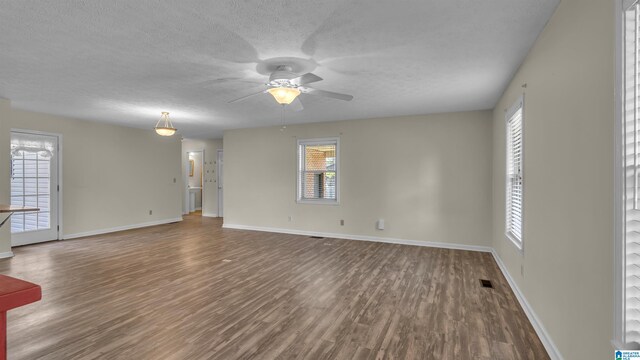 unfurnished living room featuring ceiling fan, a textured ceiling, wood finished floors, and baseboards