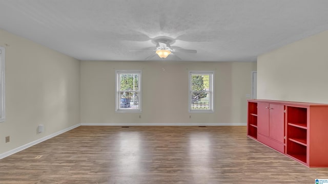 unfurnished room featuring wood finished floors, ceiling fan, baseboards, and a wealth of natural light
