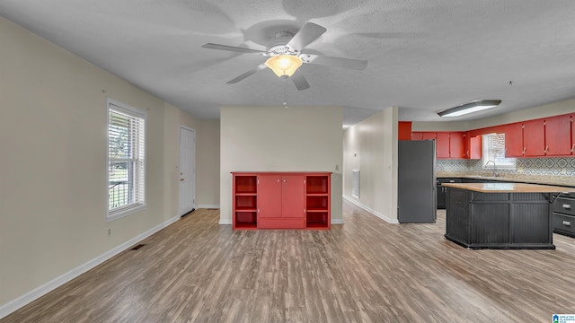 kitchen with a center island, a sink, freestanding refrigerator, a ceiling fan, and light wood-style floors