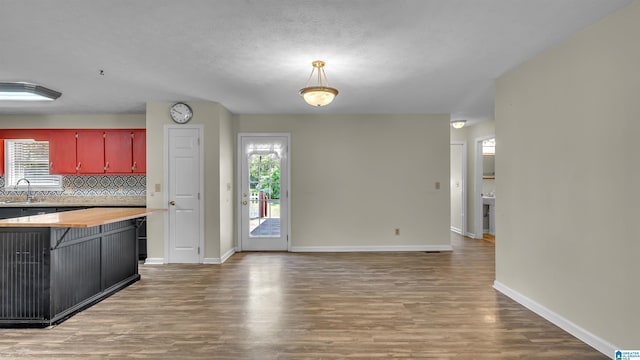 kitchen with wood counters, wood finished floors, a sink, and a healthy amount of sunlight