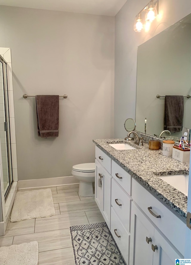 bathroom featuring a sink, toilet, a shower stall, and baseboards