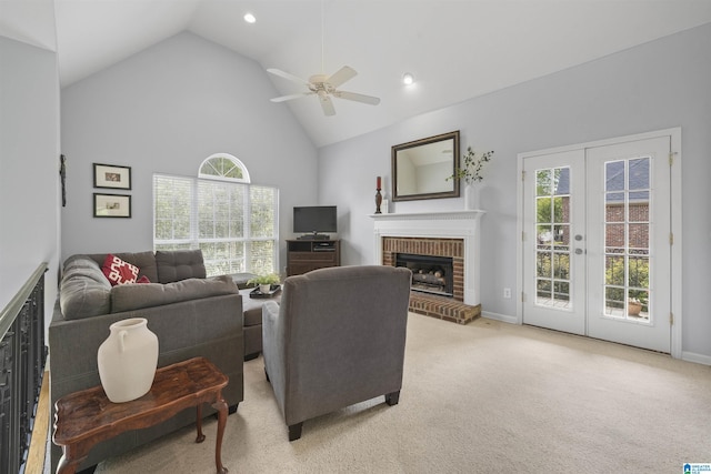 living room with a fireplace, french doors, ceiling fan, high vaulted ceiling, and light colored carpet