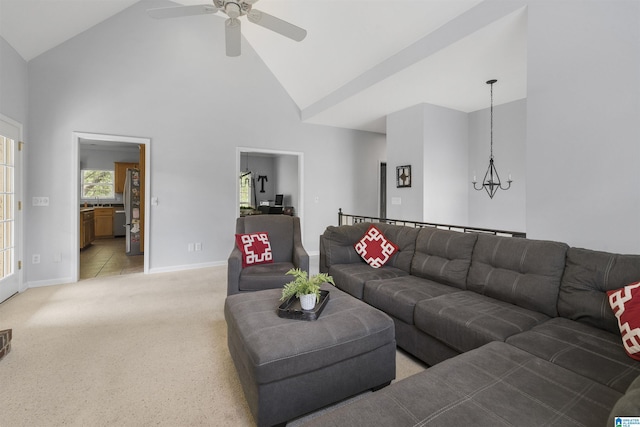living room with baseboards, high vaulted ceiling, light carpet, and ceiling fan with notable chandelier