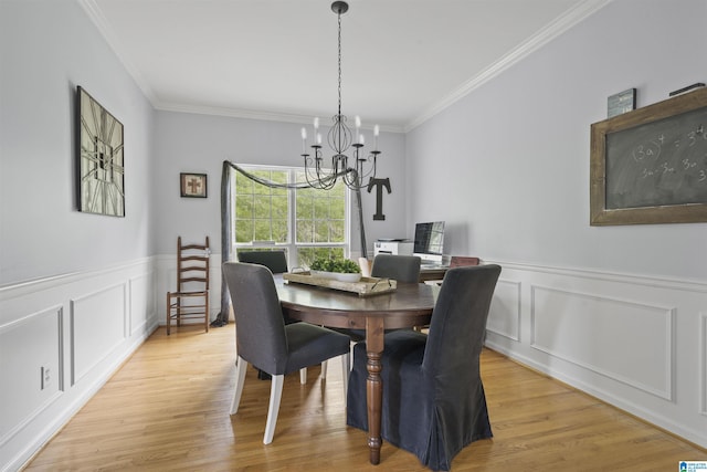 dining room with a decorative wall, ornamental molding, light wood-type flooring, and a notable chandelier