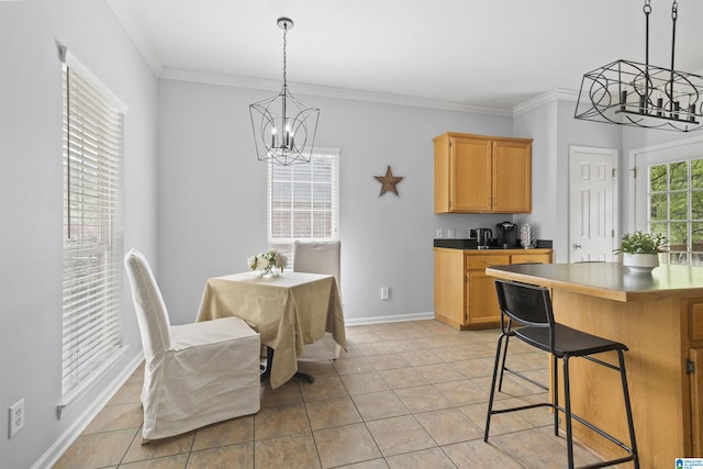 kitchen featuring hanging light fixtures, baseboards, a notable chandelier, ornamental molding, and a breakfast bar