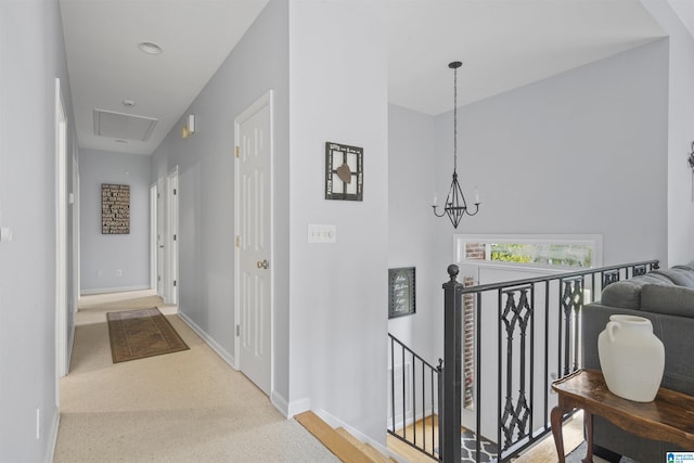 hallway featuring baseboards, an upstairs landing, and a chandelier
