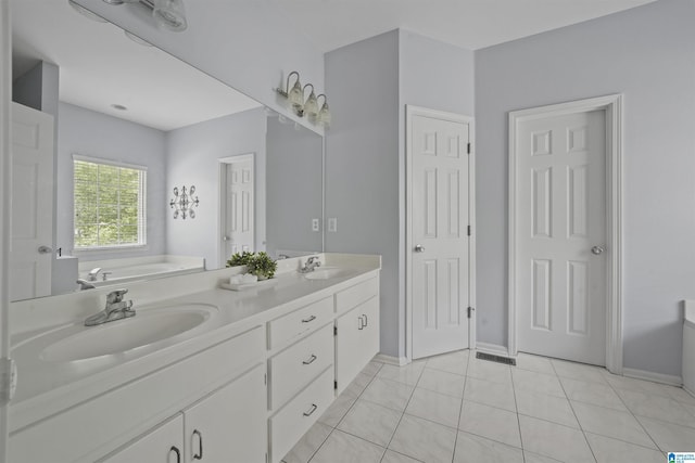 bathroom with a sink, tile patterned floors, a bath, and double vanity