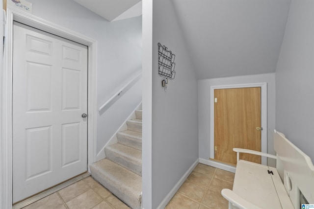 stairway with tile patterned flooring, baseboards, and lofted ceiling