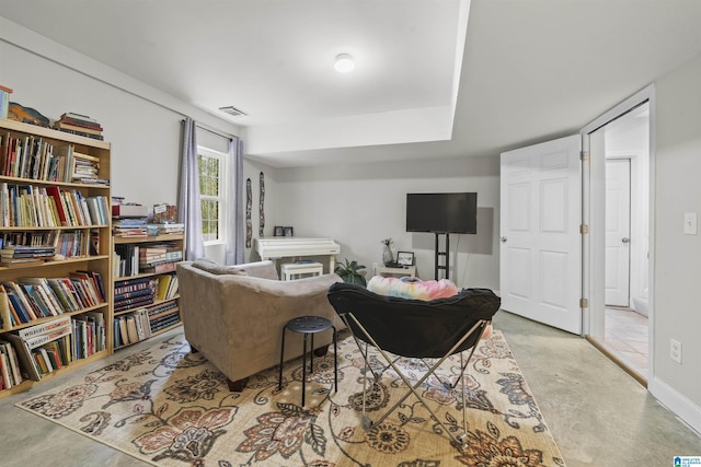 living area with concrete floors, visible vents, and baseboards