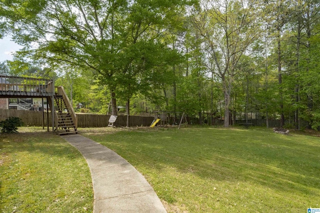 view of yard featuring fence, stairs, a wooden deck, and a playground