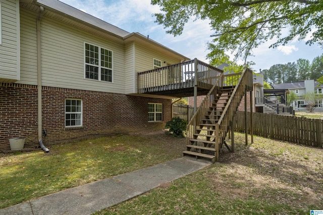 back of property featuring a deck, a yard, fence, stairs, and brick siding
