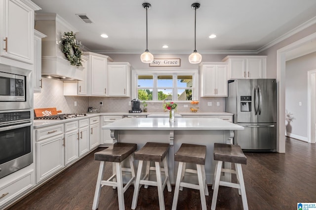 6037 Clubhouse Dr, Trussville, AL 35173 - kitchen with appliances with stainless steel finishes, white cabinetry, ornamental molding, custom exhaust hood, and a breakfast bar area