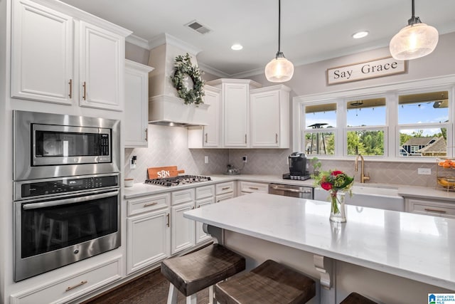 6037 Clubhouse Dr, Trussville, AL 35173 - kitchen featuring appliances with stainless steel finishes, a kitchen breakfast bar, white cabinets, ornamental molding, and decorative light fixtures