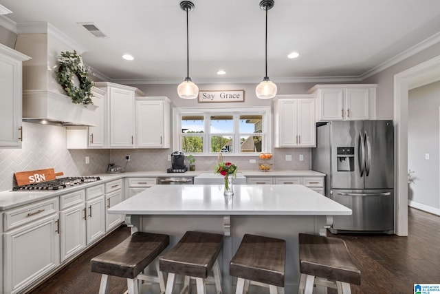 6037 Clubhouse Dr, Trussville, AL 35173 - kitchen featuring appliances with stainless steel finishes, white cabinets, crown molding, a kitchen breakfast bar, and light countertops