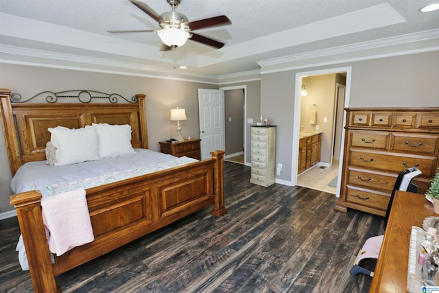 bedroom featuring ensuite bathroom, ornamental molding, dark wood-style flooring, a raised ceiling, and baseboards