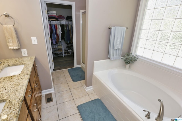 bathroom featuring a stall shower, vanity, visible vents, a walk in closet, and tile patterned floors