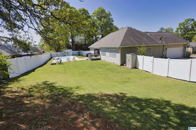 view of yard with an attached garage and a fenced backyard