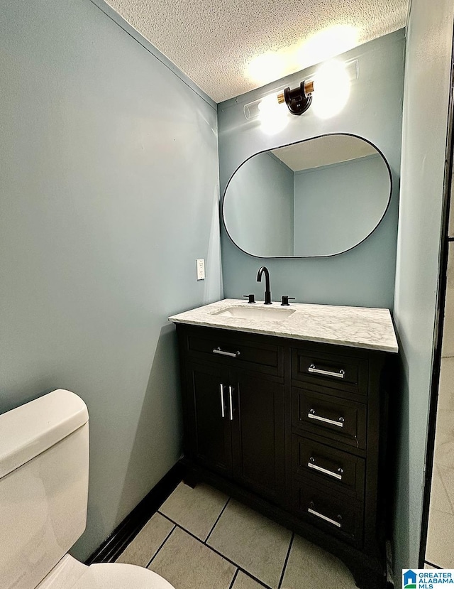 bathroom with tile patterned floors, vanity, a textured ceiling, and toilet