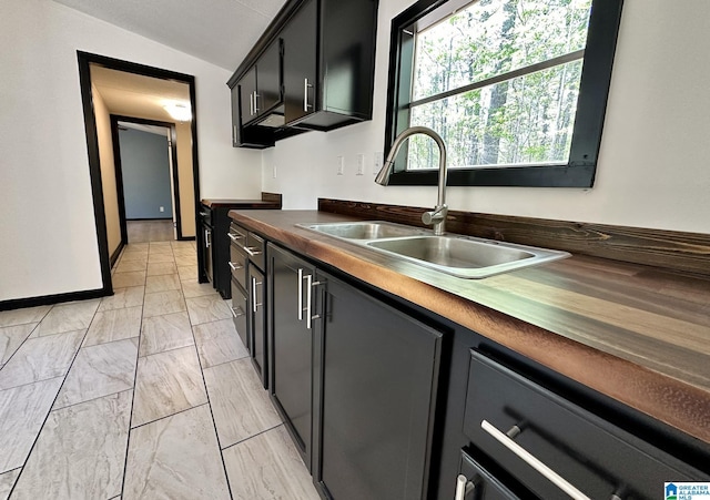kitchen with marble finish floor, a sink, dark countertops, lofted ceiling, and dark cabinetry