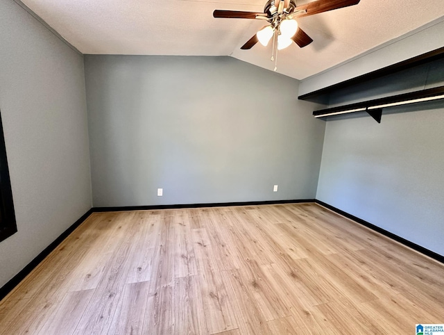 spare room featuring baseboards, light wood finished floors, vaulted ceiling, and a ceiling fan