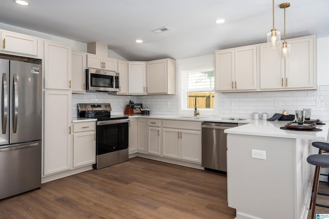 1121 Lawley St, Helena, AL 35080 - kitchen featuring stainless steel appliances, a peninsula, dark wood-style floors, a kitchen breakfast bar, and visible vents