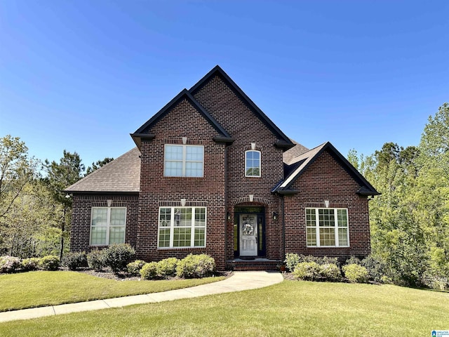 view of front of house with brick siding, roof with shingles, and a front lawn