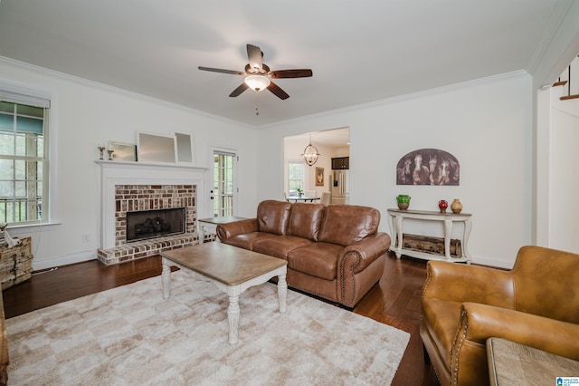 living room with baseboards, a brick fireplace, wood finished floors, ceiling fan, and crown molding
