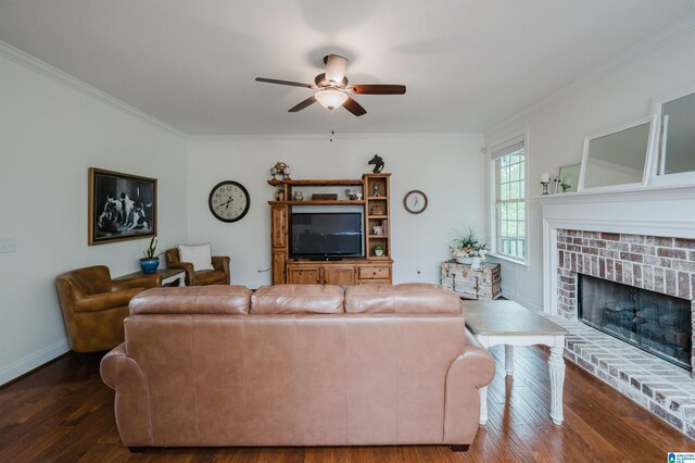 living room featuring dark wood-style floors, baseboards, a ceiling fan, a fireplace, and ornamental molding