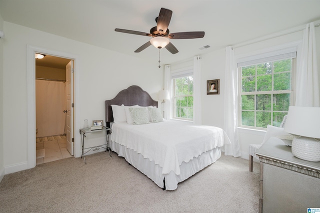 bedroom featuring ensuite bathroom, ceiling fan, light colored carpet, baseboards, and visible vents