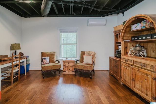sitting room with an AC wall unit, baseboards, and dark wood-style flooring