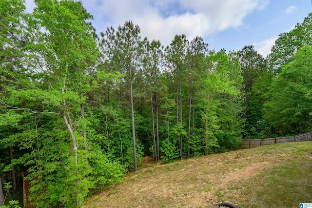 view of yard featuring fence and a wooded view