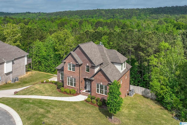 exterior space featuring brick siding, fence, and a wooded view