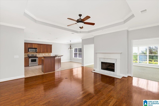 5592 Summit Pointe, Pinson, AL 35126 - unfurnished living room with ceiling fan with notable chandelier, a fireplace, a tray ceiling, light wood finished floors, and baseboards
