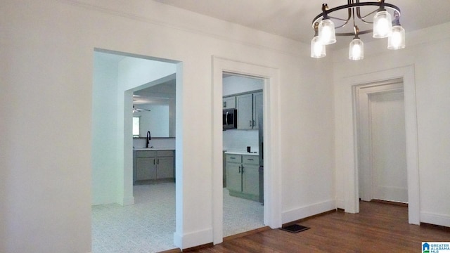 1501 Graymont Ave W, Birmingham, AL 35208 - hall featuring a chandelier, baseboards, dark wood-style flooring, and a sink
