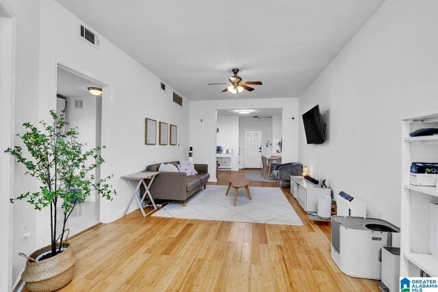 living area featuring visible vents, a ceiling fan, and light wood finished floors