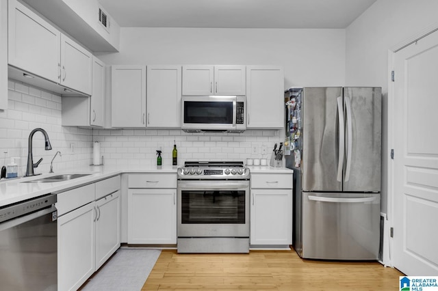 kitchen with light countertops, light wood-type flooring, a sink, and stainless steel appliances