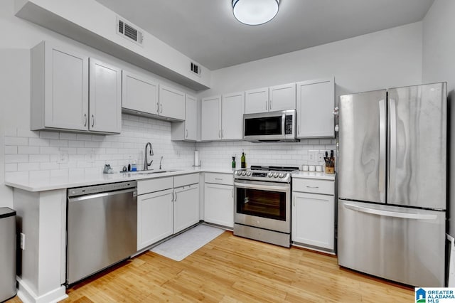 kitchen featuring light countertops, visible vents, decorative backsplash, stainless steel appliances, and a sink