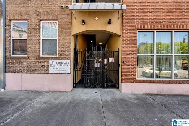 view of exterior entry with a gate and brick siding