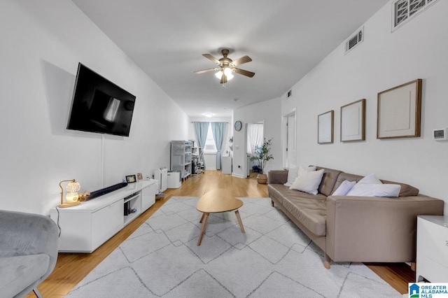 living area with light wood finished floors, visible vents, and ceiling fan