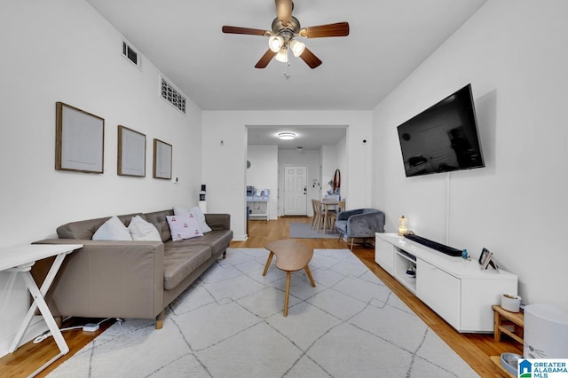 living room featuring visible vents, ceiling fan, and light wood-type flooring