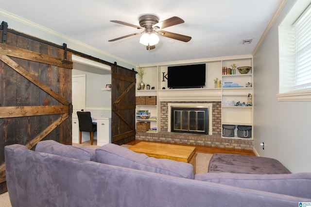 living room featuring crown molding, a ceiling fan, built in features, and a barn door