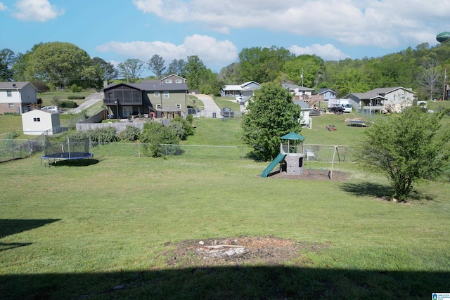 surrounding community featuring playground community, a fenced backyard, a yard, and a trampoline