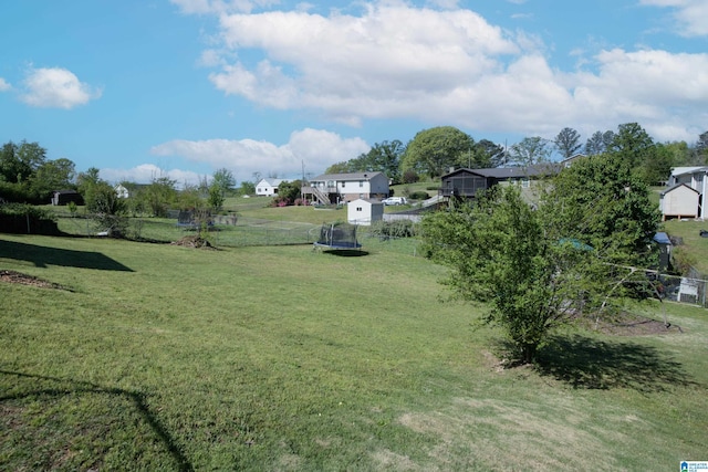 view of yard with a trampoline and fence