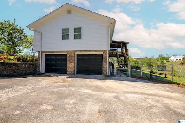 view of home's exterior featuring a gate, an attached garage, driveway, and fence